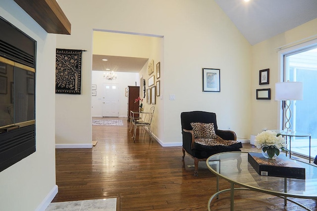 corridor with lofted ceiling, dark hardwood / wood-style floors, and a notable chandelier