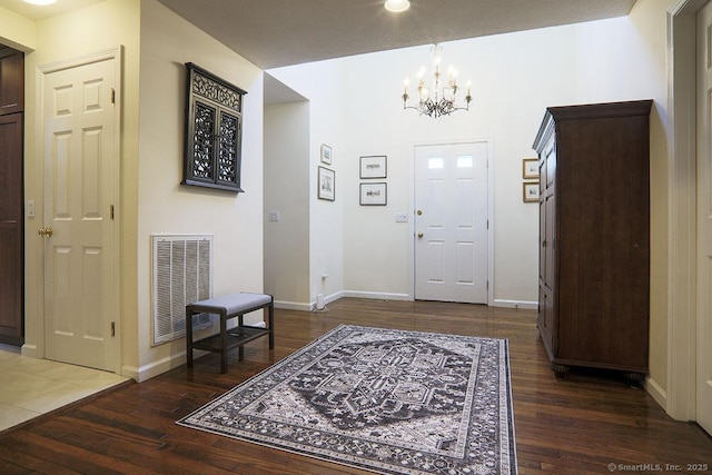 foyer entrance featuring dark wood-type flooring and an inviting chandelier