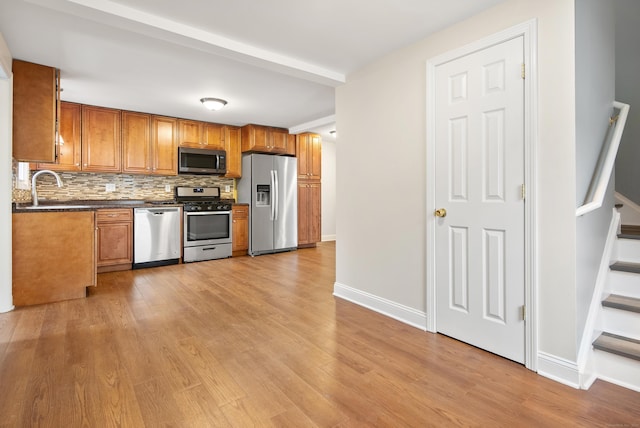 kitchen featuring decorative backsplash, stainless steel appliances, light hardwood / wood-style floors, and sink