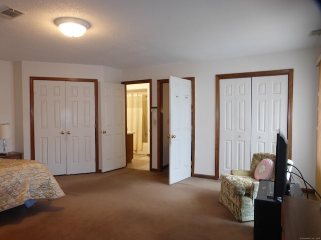 bedroom featuring light colored carpet and two closets