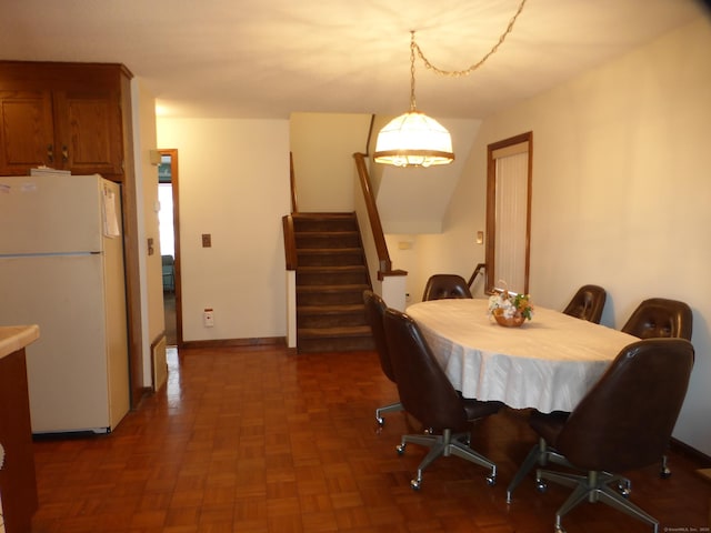 dining space featuring dark parquet flooring