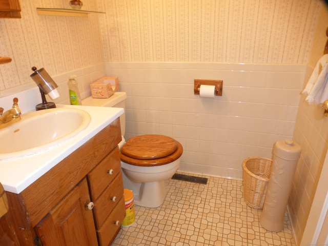 bathroom featuring toilet, vanity, tile patterned floors, and tile walls