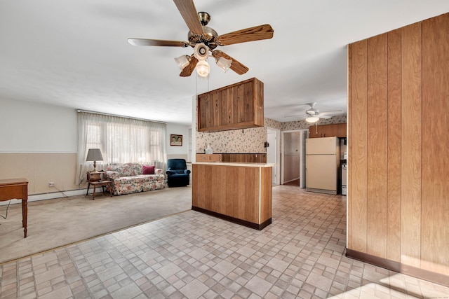 kitchen featuring light carpet, wood walls, kitchen peninsula, and white fridge