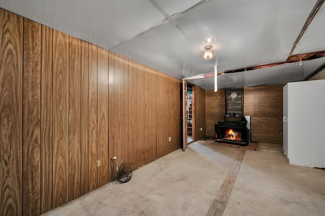 unfurnished living room featuring a wood stove and wooden walls