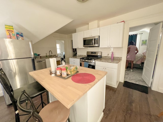 kitchen featuring a kitchen bar, appliances with stainless steel finishes, dark hardwood / wood-style floors, and white cabinetry