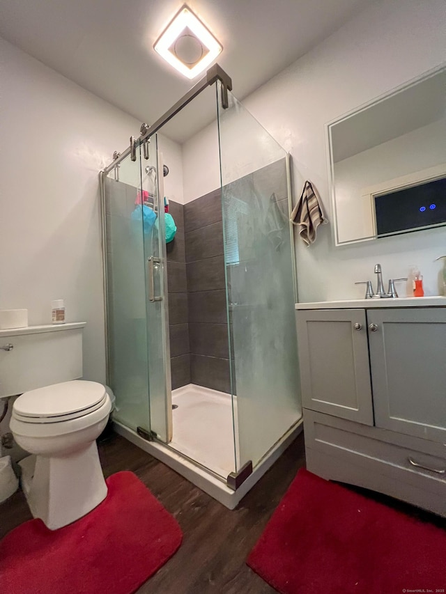 bathroom featuring hardwood / wood-style flooring, toilet, an enclosed shower, and vanity