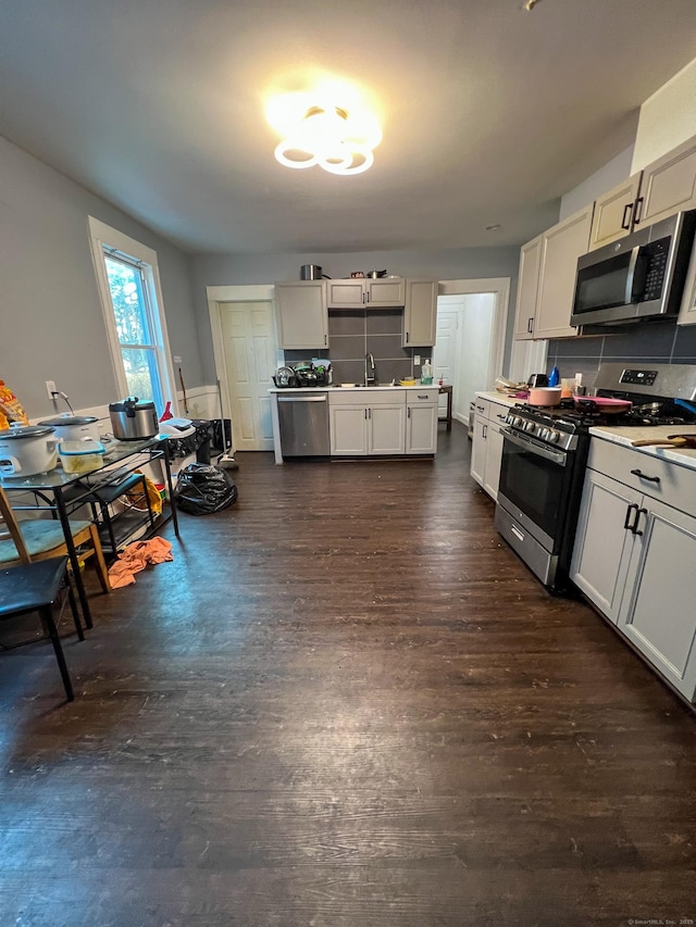 kitchen featuring sink, decorative backsplash, dark hardwood / wood-style flooring, white cabinetry, and stainless steel appliances