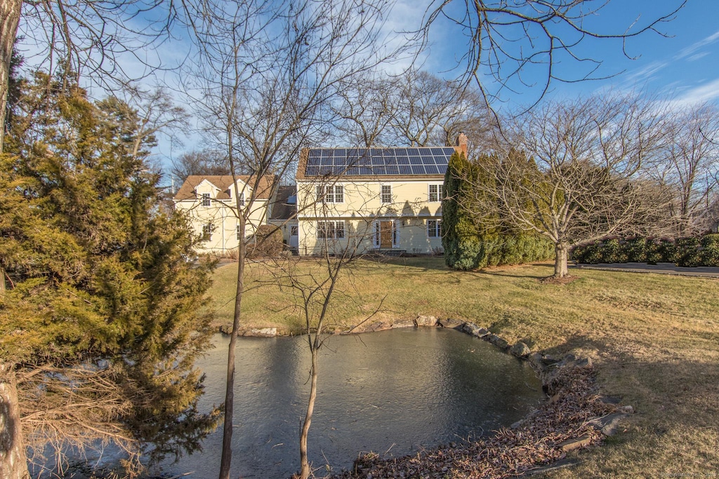 back of property with a yard and solar panels