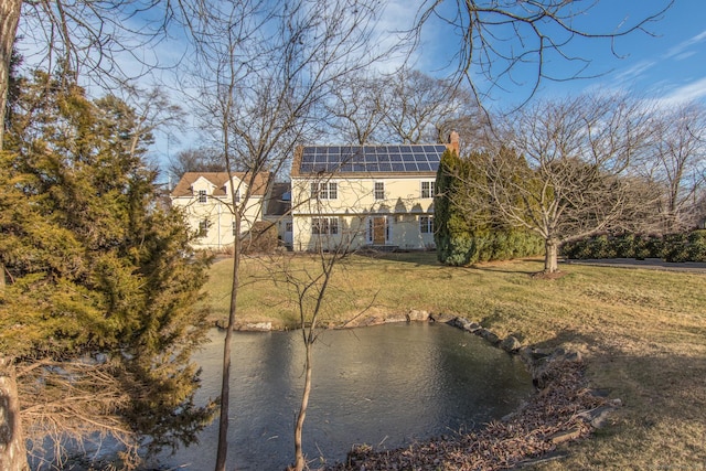 back of property with a yard and solar panels