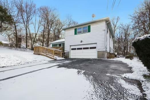 view of snowy exterior with a garage and a wooden deck