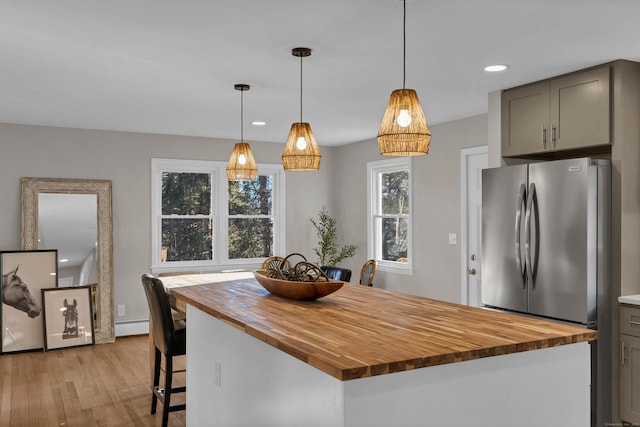 kitchen featuring a baseboard radiator, stainless steel fridge, pendant lighting, gray cabinets, and a kitchen island