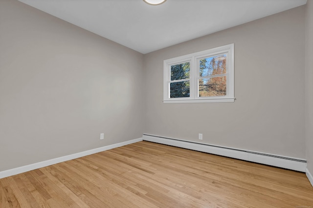 empty room with light hardwood / wood-style flooring and a baseboard heating unit