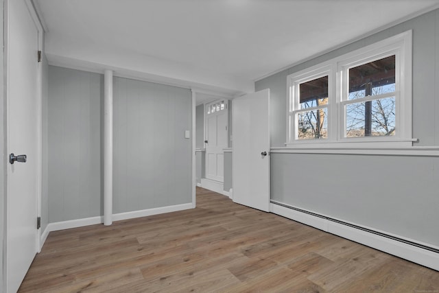 spare room featuring baseboard heating and light wood-type flooring