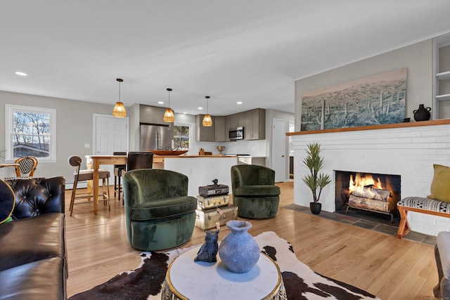 living room with a brick fireplace, a baseboard radiator, and light wood-type flooring