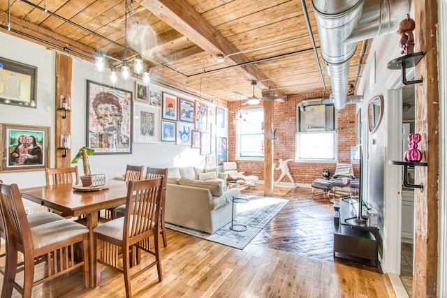 dining space featuring ceiling fan, beamed ceiling, brick wall, wood ceiling, and light wood-type flooring