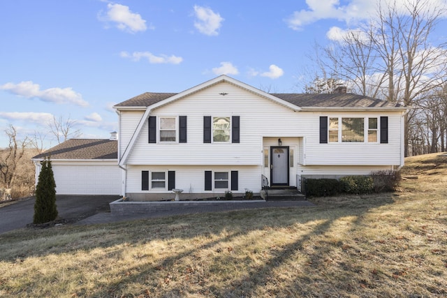 bi-level home featuring a garage and a front lawn