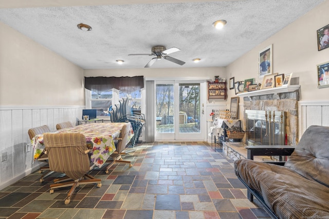 interior space featuring a textured ceiling, ceiling fan, and a stone fireplace