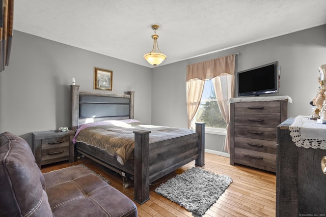 bedroom with a textured ceiling and light hardwood / wood-style floors