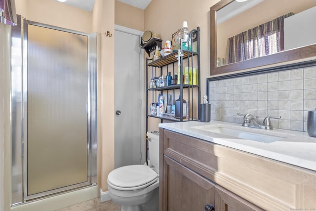 bathroom with tile patterned flooring, toilet, vanity, a shower with door, and decorative backsplash