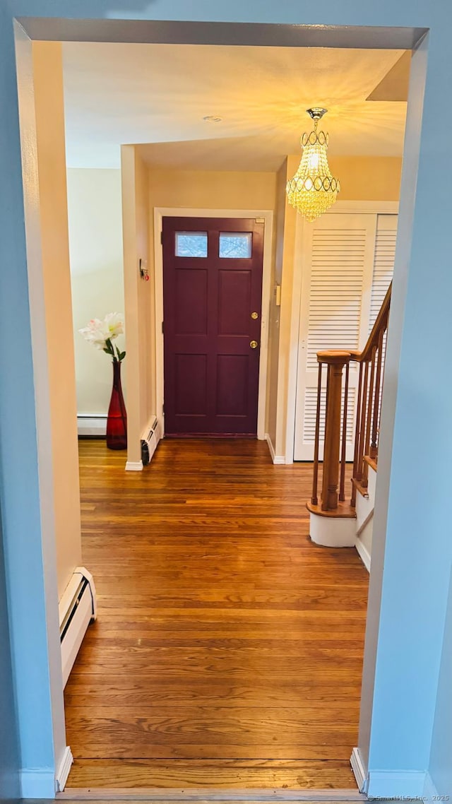 entryway with baseboard heating, a chandelier, and wood-type flooring