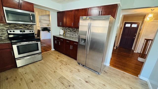 kitchen featuring appliances with stainless steel finishes, light hardwood / wood-style floors, and hanging light fixtures