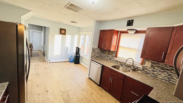 kitchen featuring sink, stainless steel appliances, baseboard heating, tasteful backsplash, and light stone counters