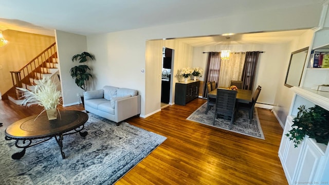 living room with dark hardwood / wood-style flooring, a baseboard heating unit, and an inviting chandelier