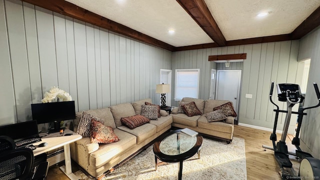 living room featuring beam ceiling, light hardwood / wood-style flooring, a baseboard heating unit, wood walls, and a textured ceiling