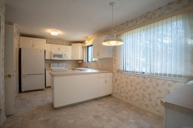 kitchen with white appliances, kitchen peninsula, white cabinets, decorative light fixtures, and sink