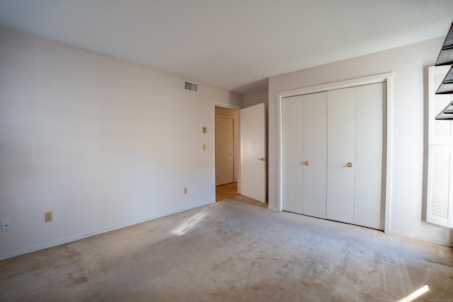 unfurnished bedroom featuring light colored carpet and a closet