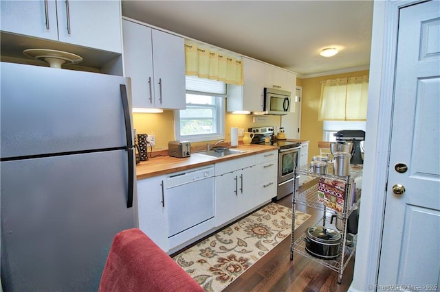 kitchen with dark wood-type flooring, sink, stainless steel appliances, and white cabinetry