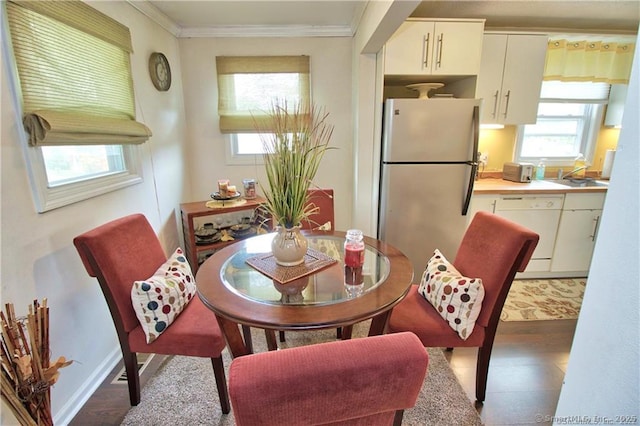 dining area with dark hardwood / wood-style flooring, crown molding, and sink