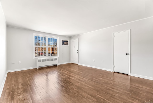 spare room featuring dark hardwood / wood-style floors and radiator