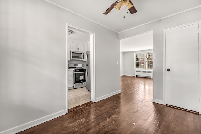 interior space with hardwood / wood-style floors, appliances with stainless steel finishes, ceiling fan, radiator heating unit, and white cabinets