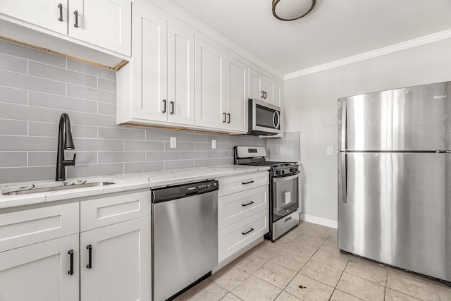 kitchen featuring stainless steel appliances, sink, white cabinetry, decorative backsplash, and light stone countertops