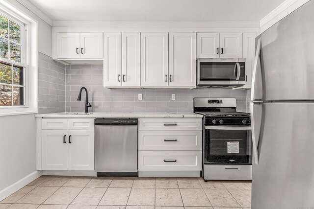 kitchen with stainless steel appliances, sink, white cabinetry, light tile patterned flooring, and tasteful backsplash