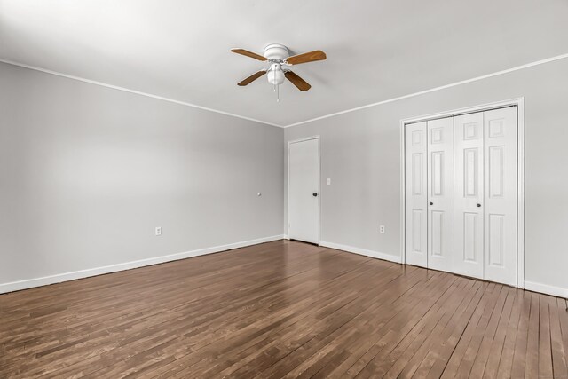 unfurnished bedroom with ceiling fan, ornamental molding, a closet, and dark hardwood / wood-style floors