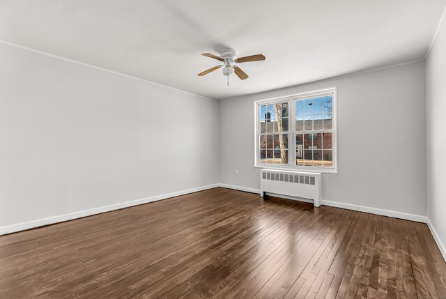 unfurnished room featuring dark wood-type flooring, ceiling fan, and radiator heating unit