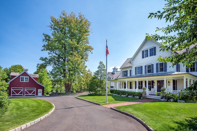 view of front facade featuring an outdoor structure, covered porch, and a front lawn