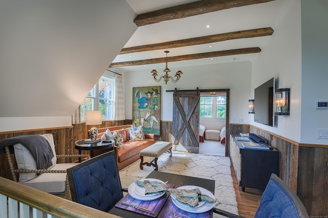 living room with plenty of natural light, beamed ceiling, a barn door, and an inviting chandelier