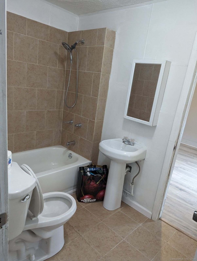 full bathroom featuring toilet, tiled shower / bath combo, tile patterned floors, and sink