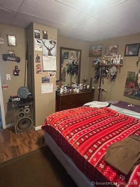 bedroom featuring a drop ceiling and hardwood / wood-style floors