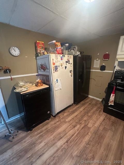 kitchen with black appliances, light hardwood / wood-style flooring, and white cabinetry