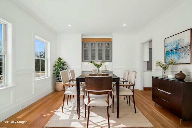 dining area with ornamental molding and light hardwood / wood-style floors