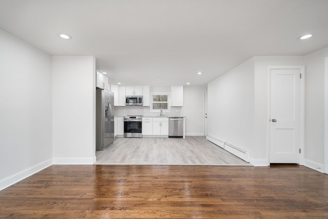 unfurnished living room with a baseboard radiator, light hardwood / wood-style flooring, and sink