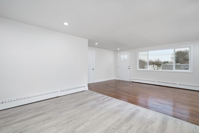 empty room with a baseboard heating unit and light hardwood / wood-style flooring