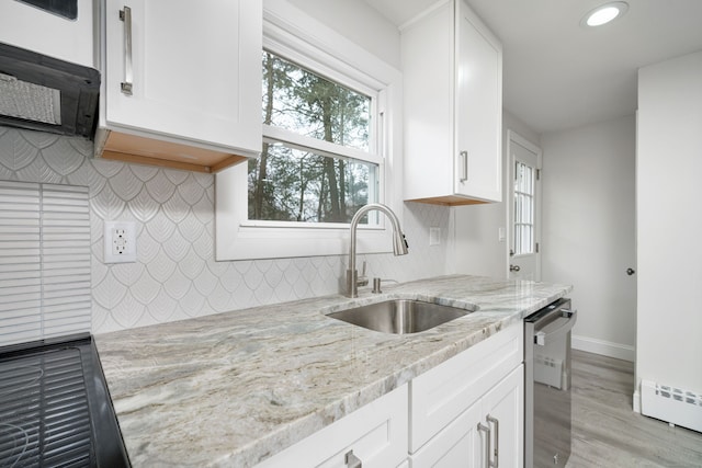 kitchen with light stone countertops, white cabinets, dishwasher, and sink