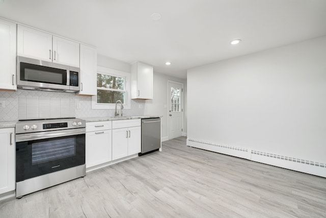 kitchen with white cabinets, a baseboard heating unit, light stone countertops, and stainless steel appliances