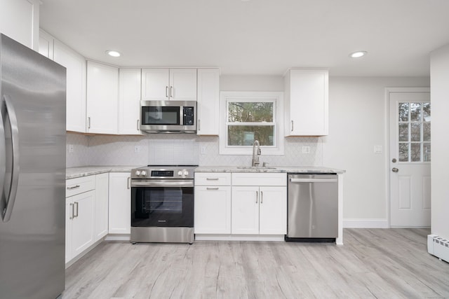 kitchen with light stone countertops, sink, white cabinetry, and stainless steel appliances