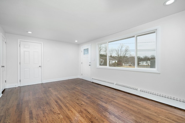 unfurnished room featuring baseboard heating and dark hardwood / wood-style flooring